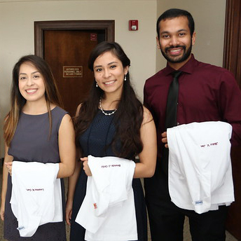 two pharmacy students smiling with white coats